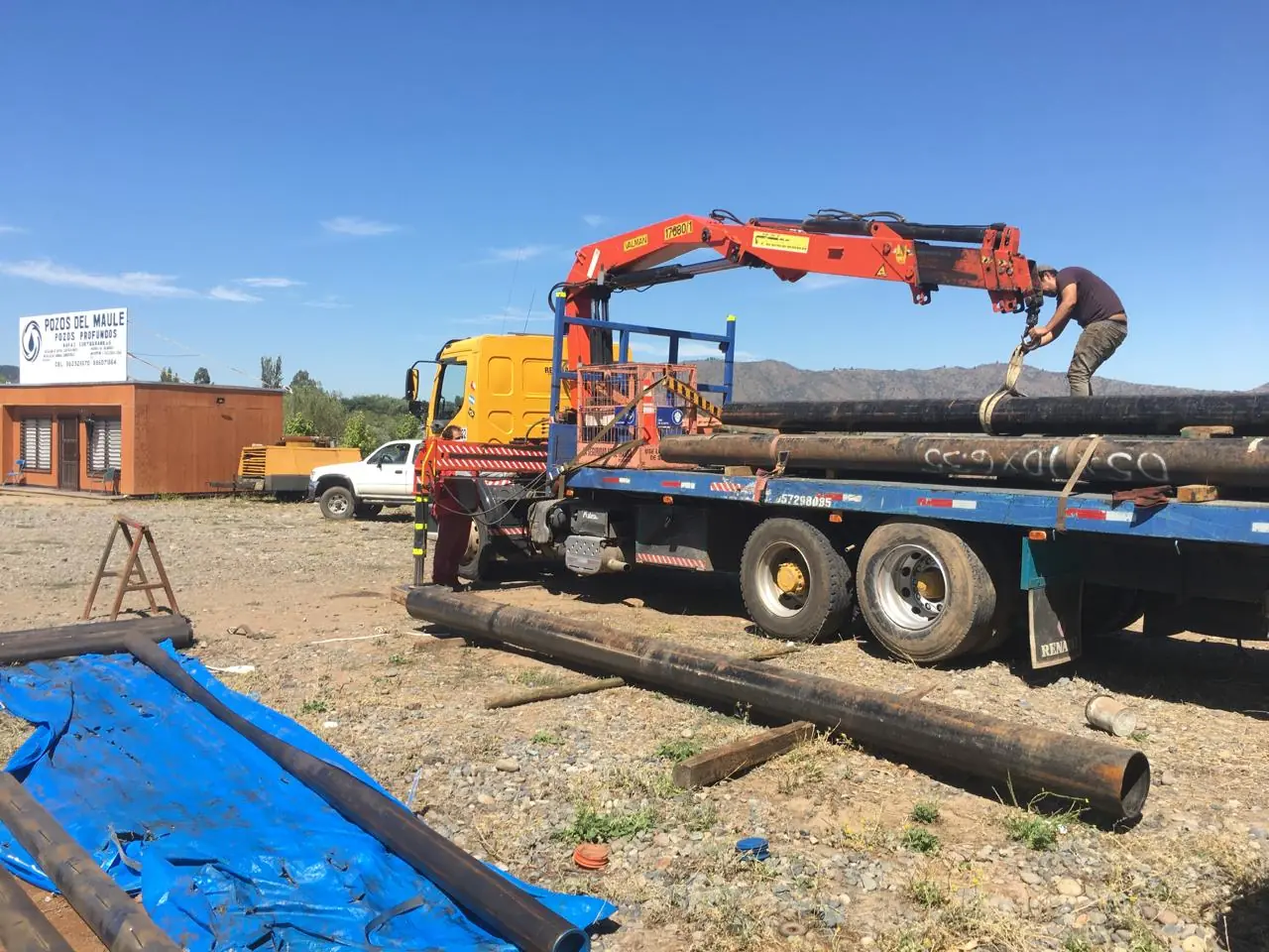 Camión grúa de Pozos del Maule cargando tuberías de entubación en terreno